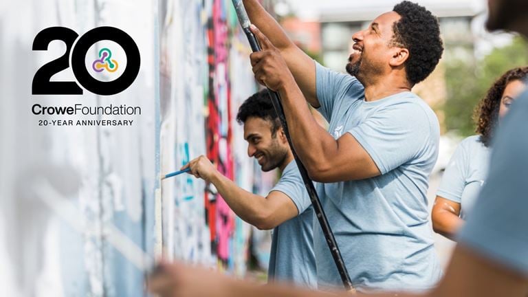 Volunteers paint a community mural, celebrating the Crowe Foundation’s 20-year legacy and impact.