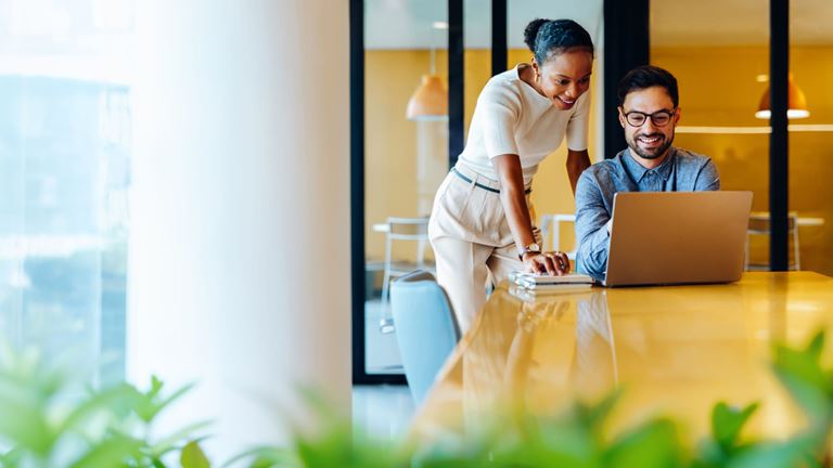 Business professionals collaborate on artificial intelligence solutions using a laptop.