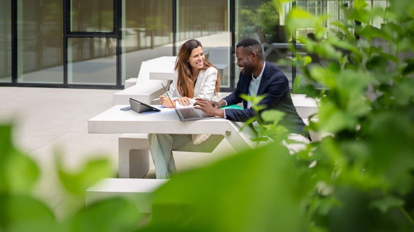 Fintech professionals collaborating with laptops in an outdoor workspace