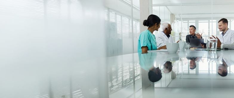 Healthcare professionals meet to discuss strategy, representing collaboration to address financial and regulatory challenges.