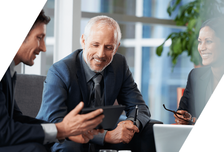 Executives review pricing data on a tablet, representing margin improvement and data-driven pricing strategy after an acquisition.