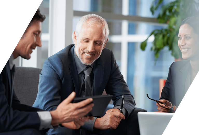 Executives review pricing data on a tablet, representing margin improvement and data-driven pricing strategy after an acquisition.