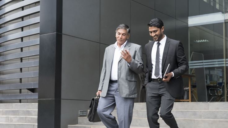 Two banking employees leaving the office and discussing strategic risk management.