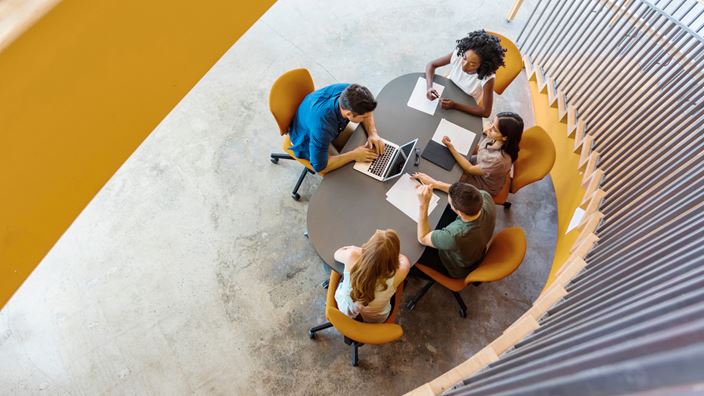 A diverse group of professionals engaged in discussion around a conference table, emphasizing collaboration and strategy.