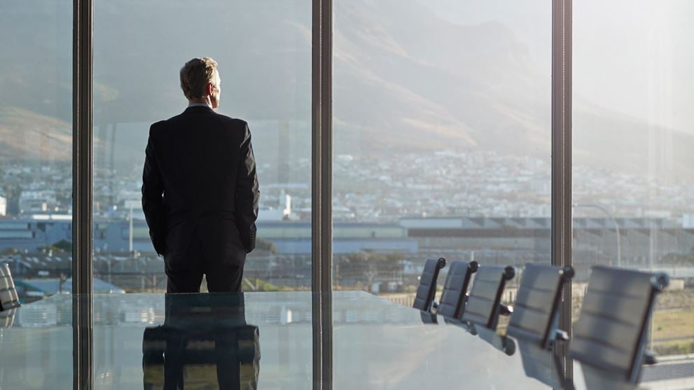 Businessman looks out of the window pondering quarterly banking M&A updates