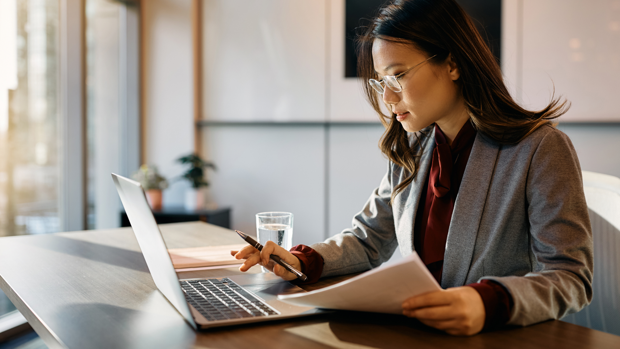Professional reviews documents and data on a laptop, representing AI-supported decision-making in the public sector.