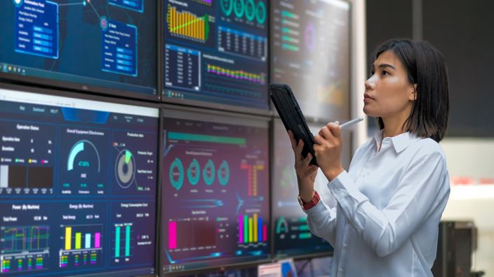 A woman in a white shirt examines a tablet, discussing how manufacturers can automate workflows with Microsoft tools and AI.