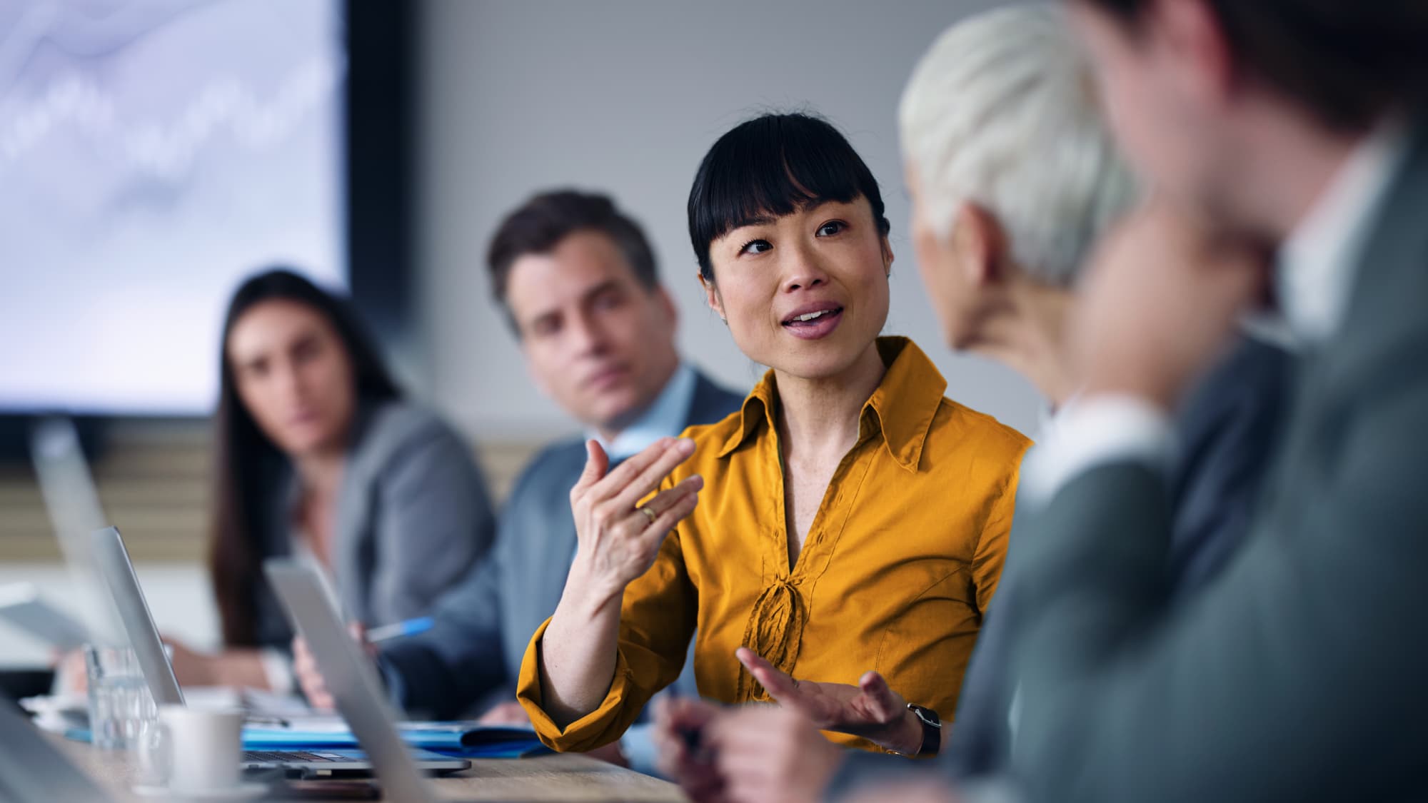 Professional woman leading a discussion during a business meeting on HITRUST updates in Q3 2025.