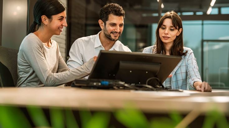 Team reviews information on a screen, representing ongoing collaboration to maintain AI governance and adapt to evolving risks.