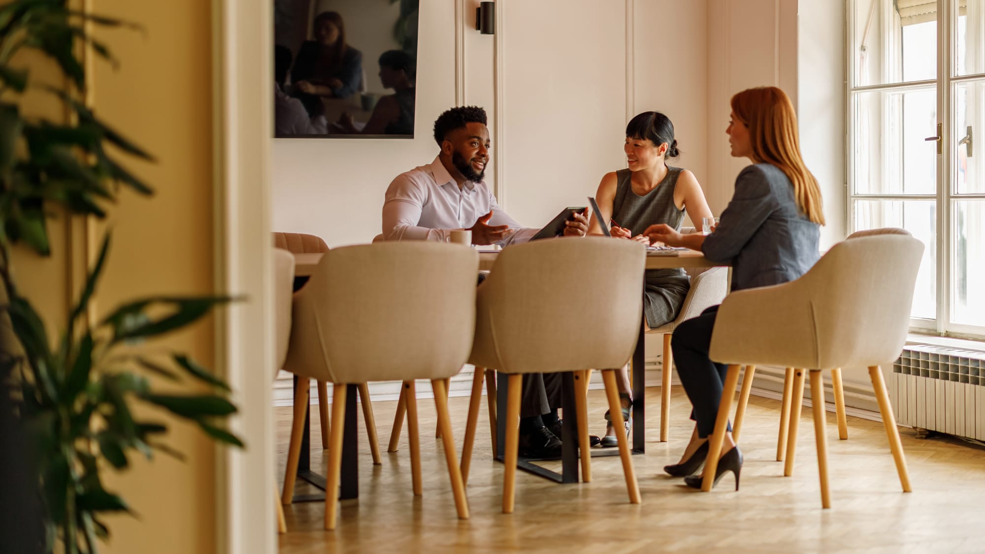 Team meets around a table, representing collaboration and sharing updates in a quarterly HITRUST cybersecurity newsletter.