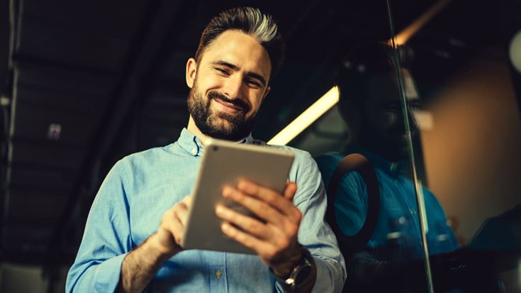 Professional using a tablet in a modern office, representing digital transformation, cybersecurity, cloud technology, and secure business solutions.