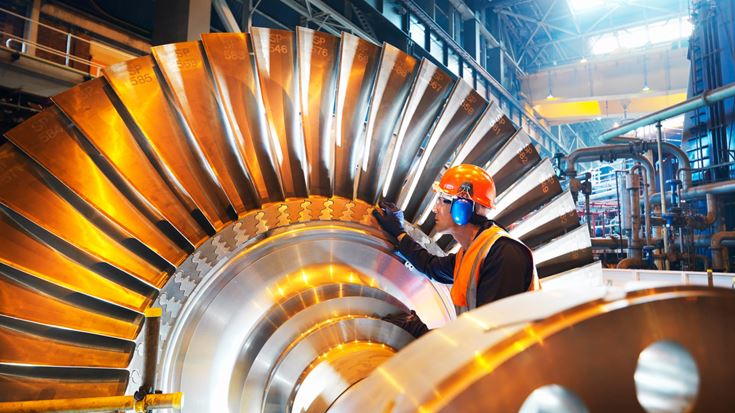 Manufacturing worker inspects industrial equipment supporting energy-intensive operations.