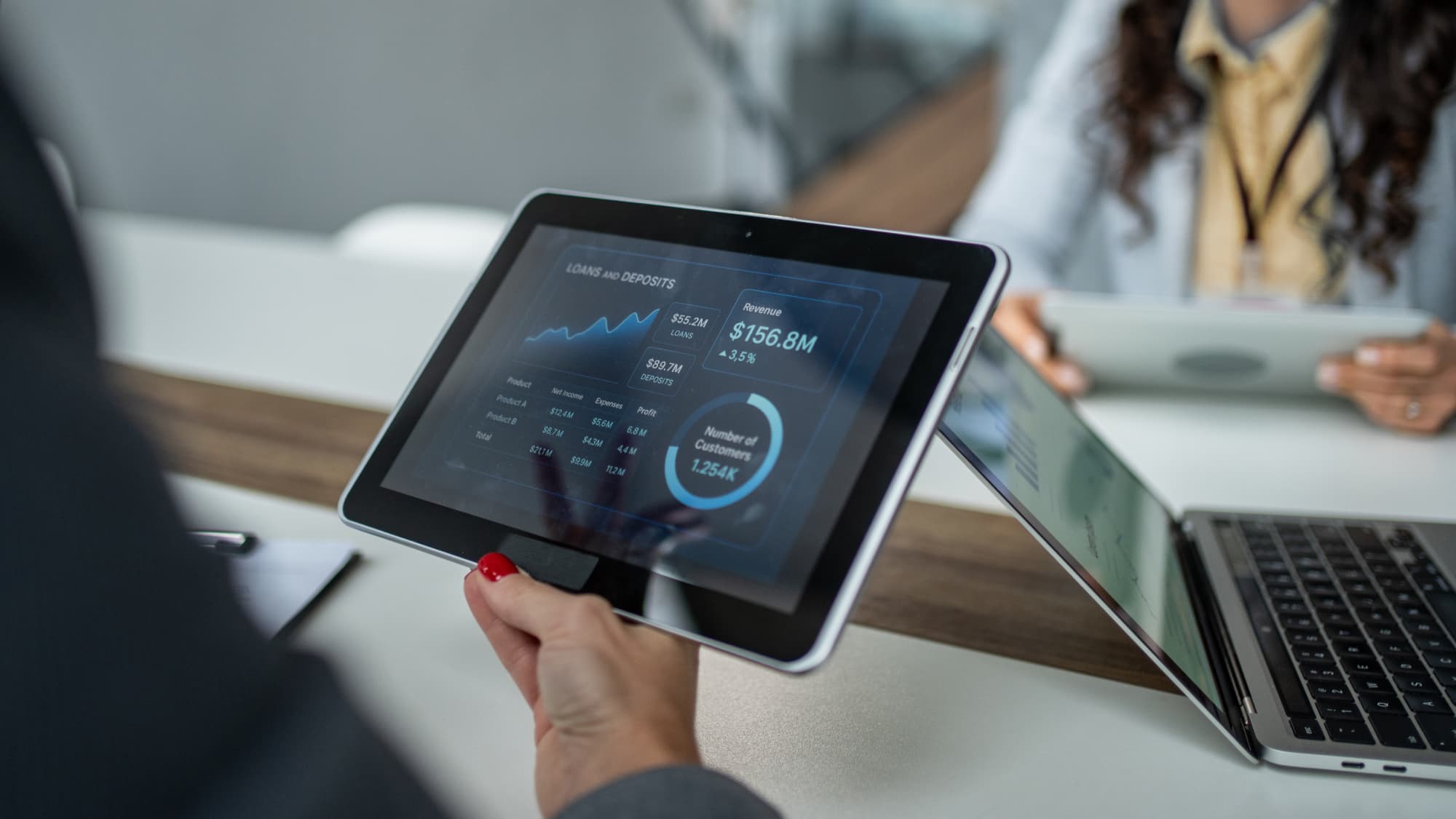 An individual holding a tablet displaying financial data.