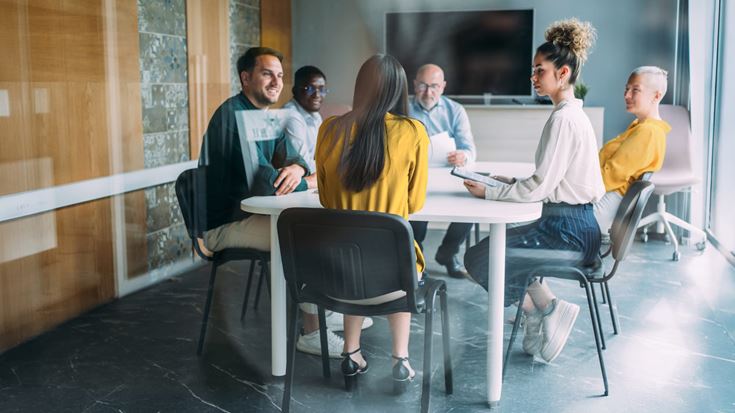 Professionals meet around a conference table, representing benefit plan discussions and compliance with the Short Plan Year Rule.