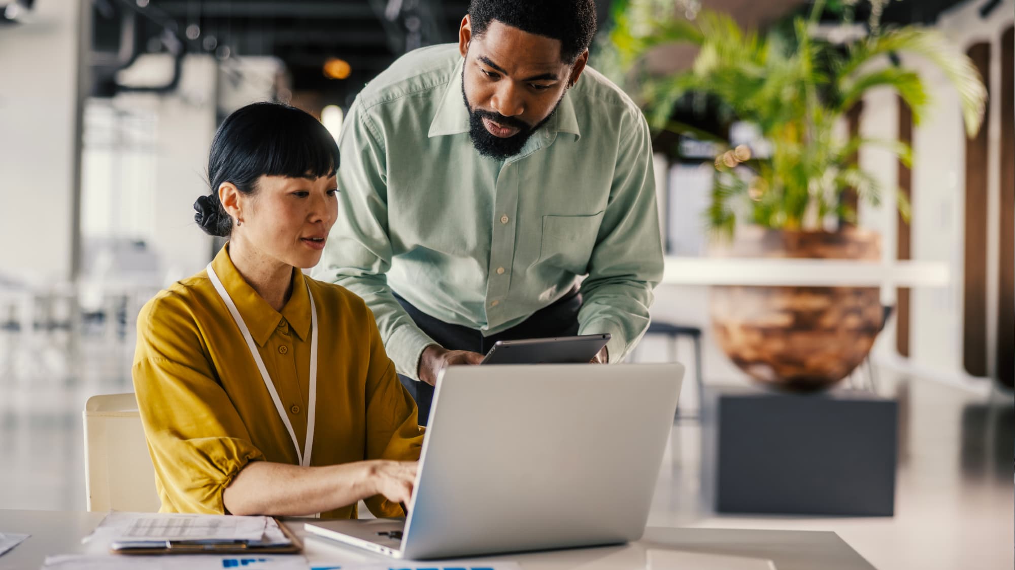 Two professionals review data on a laptop and tablet, representing model risk governance and oversight for investment managers.