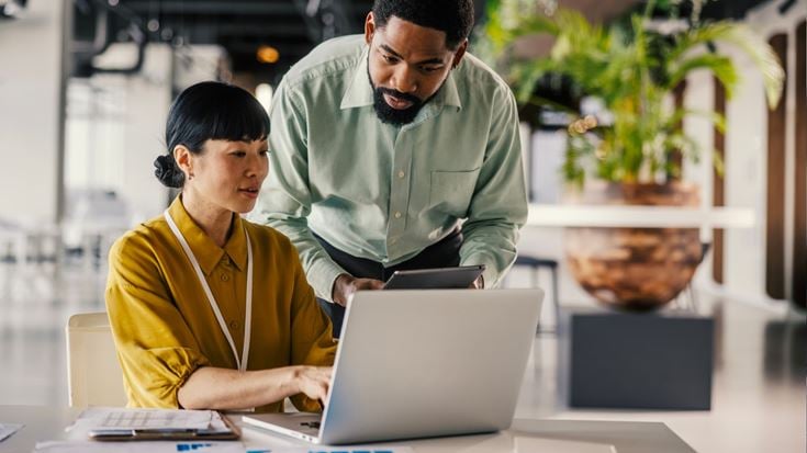 Two professionals review data on a laptop and tablet, representing model risk governance and oversight for investment managers.
