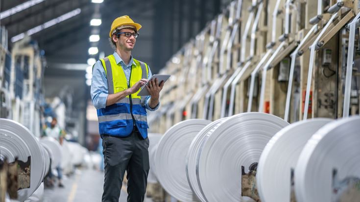 Factory worker monitors plastics production data to improve efficiency and operational visibility.