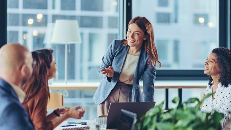 Business professional leading a collaborative team meeting in a modern office, discussing CRM strategy, digital transformation, and customer engagement.