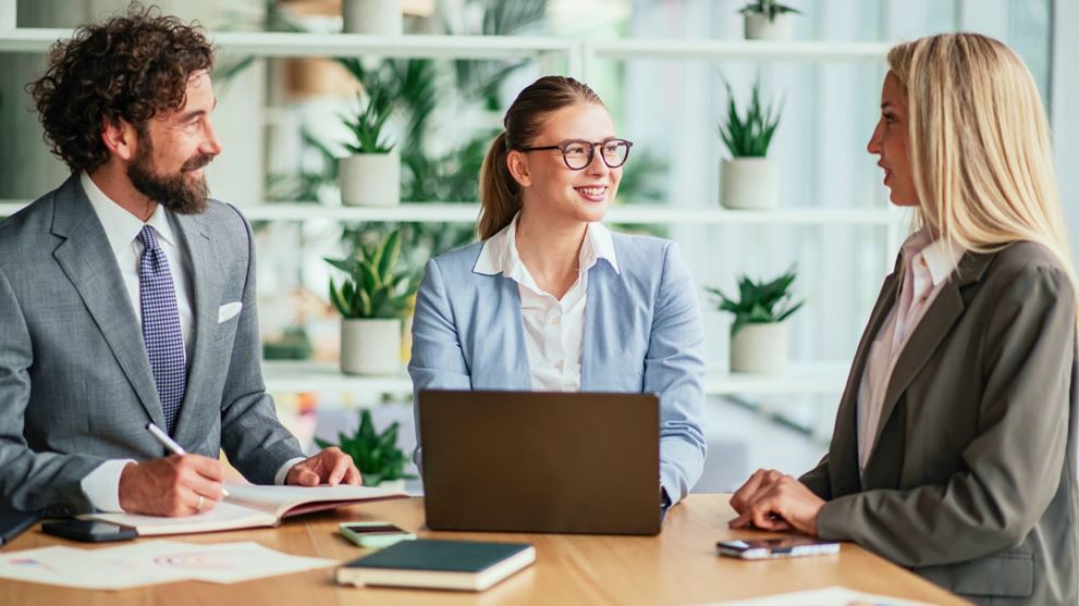 Business professionals collaborating in a modern office meeting with a laptop discussing corporate strategy