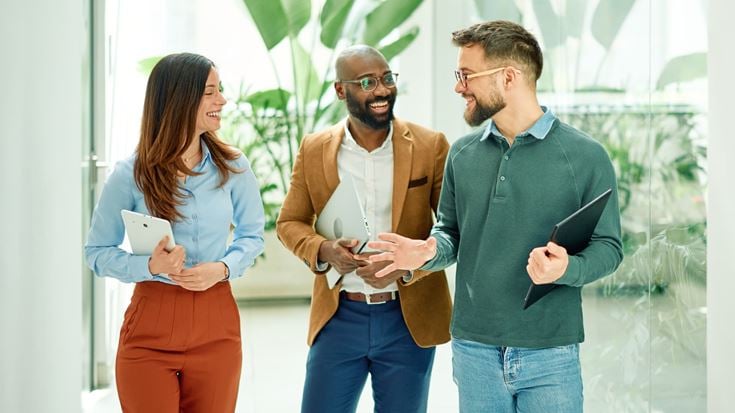Three business professionals collaborating with digital devices in a modern office, representing responsible AI, AI agents, and enterprise innovation.