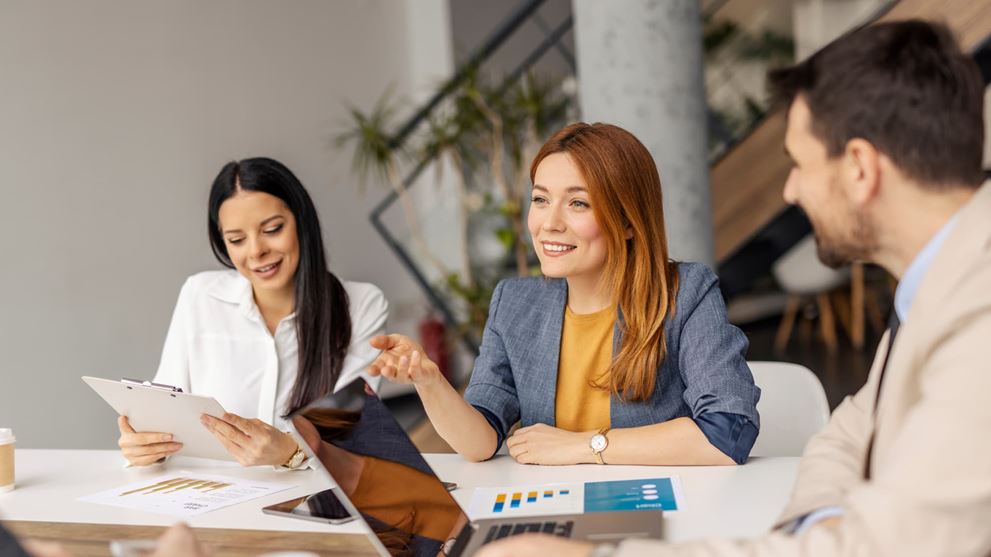 Two business professionals reviewing financial reports on a laptop, representing employee benefit plan compliance and DOL VFCP self-correction.