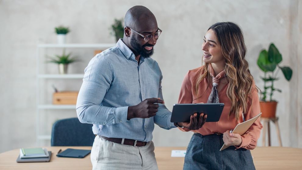 Fintech professionals review information on a tablet to assess cybersecurity risks.