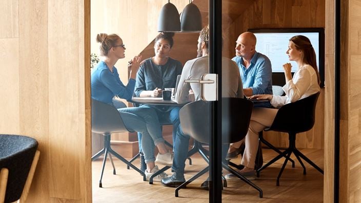 A group of professionals seated around a table in a meeting room, discussing first quarter 2025 financial reporting updates.