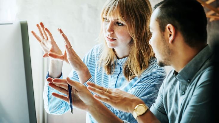 Two people discuss and gesture at a computer screen during a webinar on human-centered GRC technology approaches.