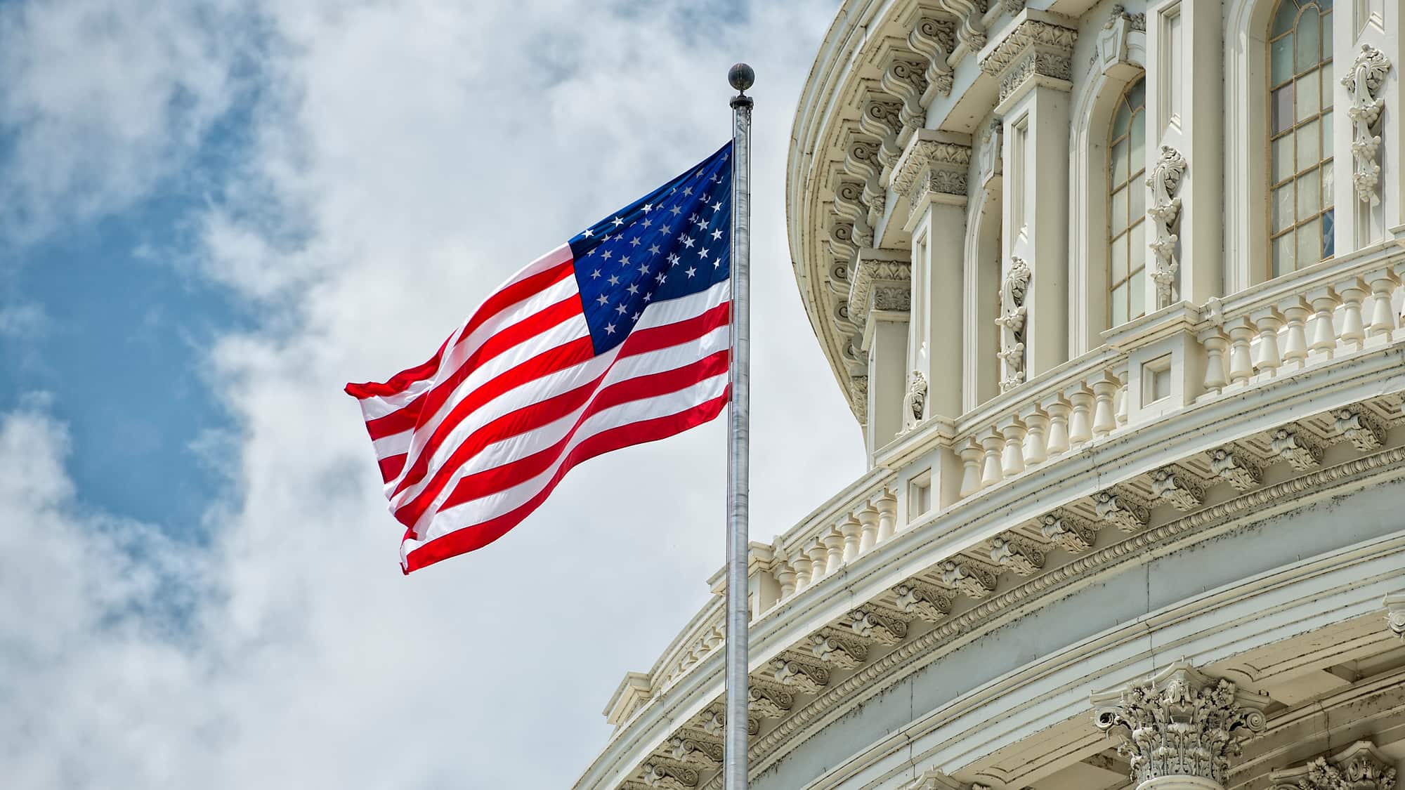 U.S. flag waves in front of a government building, symbolizing federal legislation related to the One Big Beautiful Bill Act.