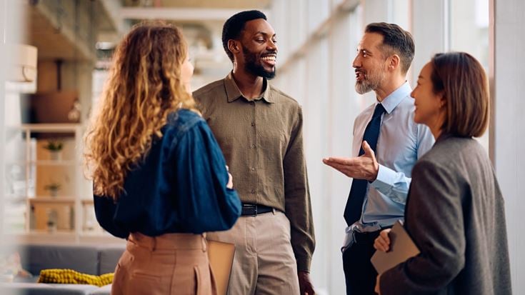 Four business professionals engage in a group discussion in a modern office.