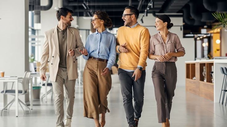 Four professionals walk and talk in a modern office, representing post-conference collaboration on SEC and PCAOB developments.