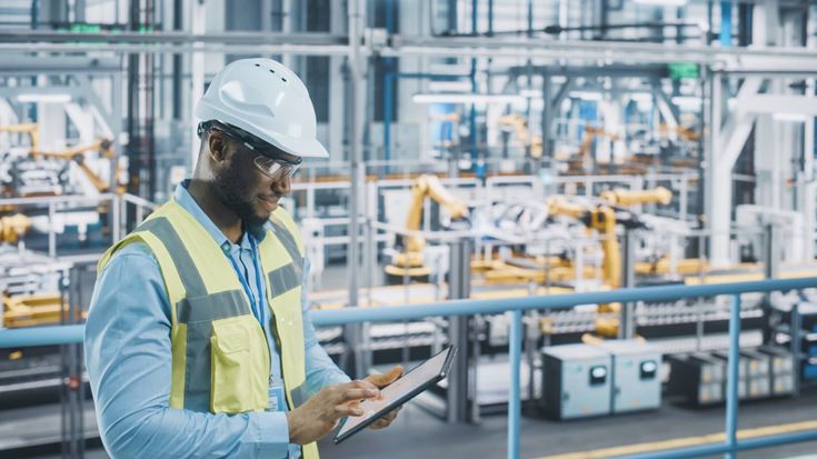 Manufacturing professional reviewing information on a tablet.