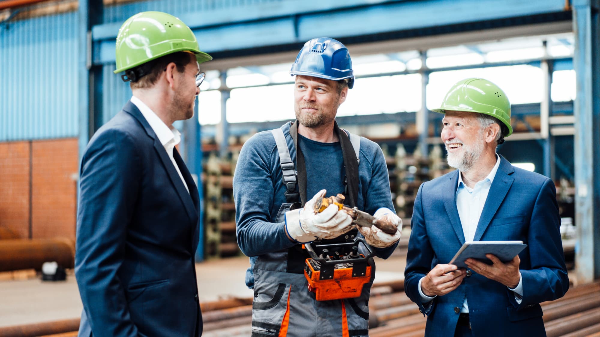 Manufacturing leaders and a plant worker discuss operations on the factory floor during an ERP implementation project.