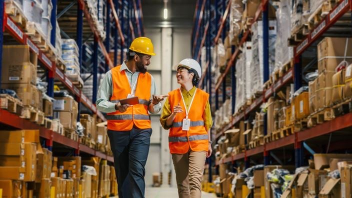 Warehouse employees review inventory while walking through storage aisles to improve inventory management and customer service.