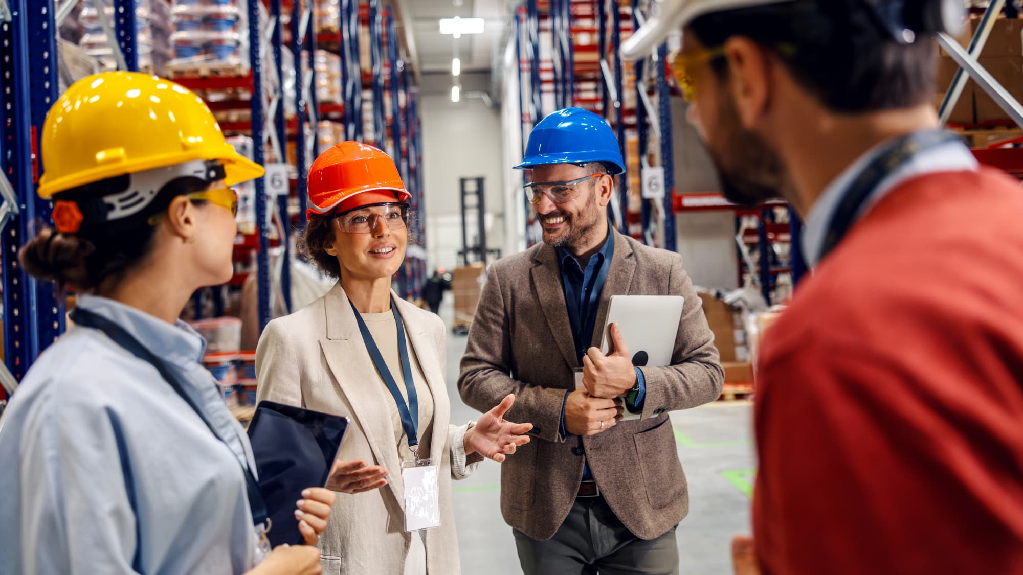 Manufacturing leaders gathered in a warehouse discuss performance management improvements.