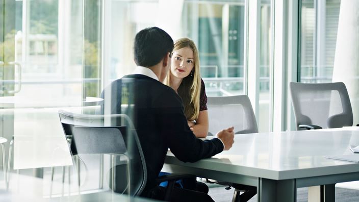 A man and woman collaborate at a table in an office, discussing the Crowe Y-Hire™ solution for NetSuite.