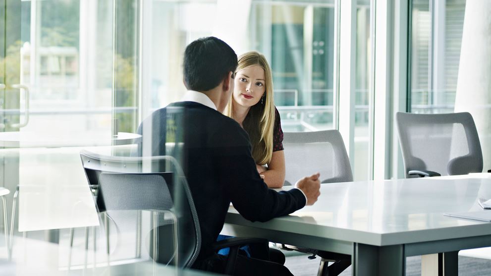 A man and woman collaborate at a table in an office, discussing the Crowe Y-Hire™ solution for NetSuite.