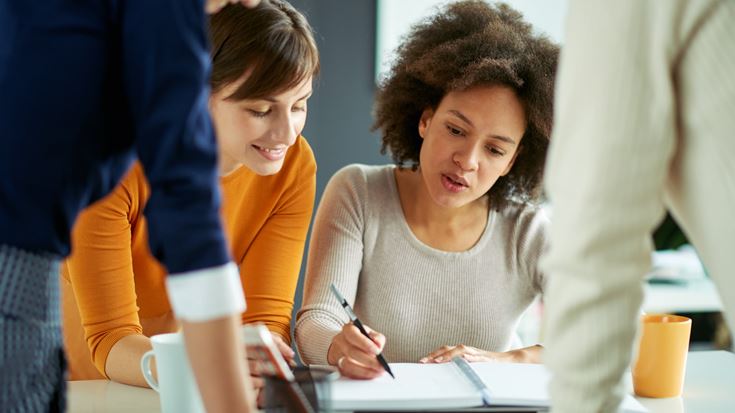 Three women work together on a project, emphasizing teamwork and women's contributions to the financial sector.