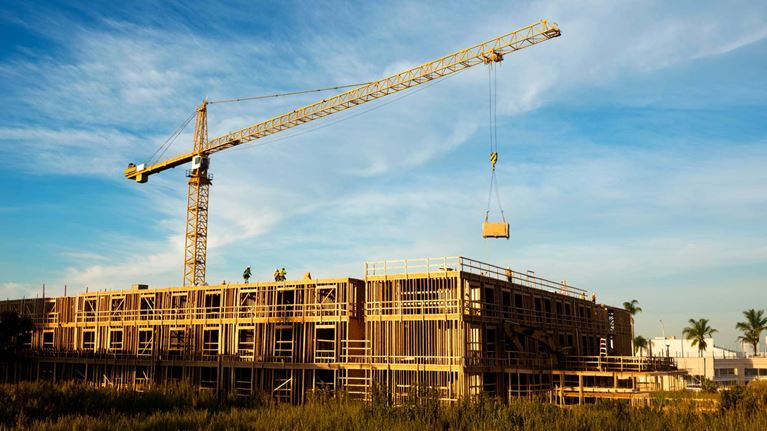 Crane lifts materials at a building site, representing construction activity and economic trends shaping contractors.