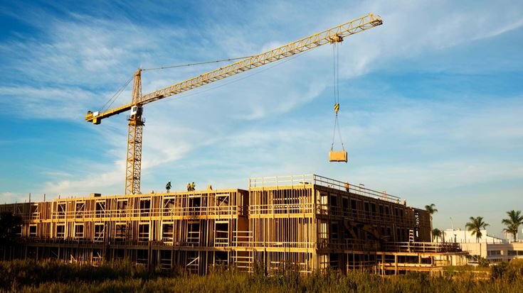 Crane lifts materials at a building site, representing construction activity and economic trends shaping contractors.