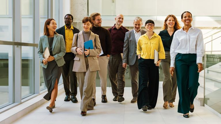 Diverse group of business professionals walking together through a modern office, representing workplace collaboration, leadership, and organizational success.