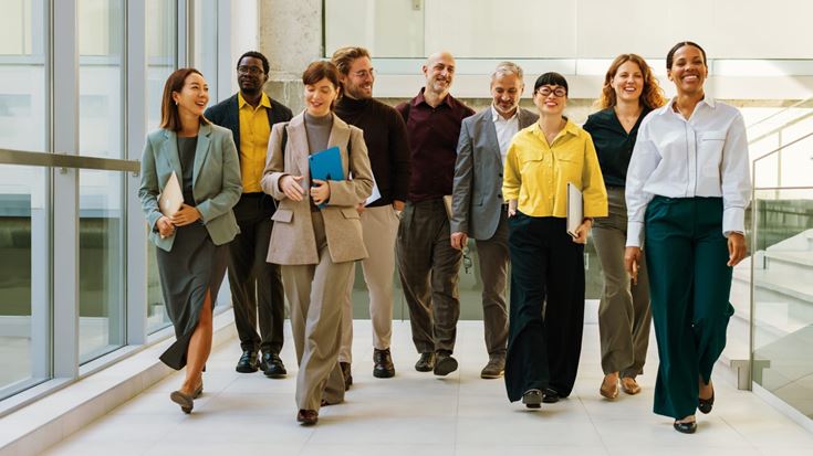Diverse group of business professionals walking together through a modern office, representing workplace collaboration, leadership, and organizational success.
