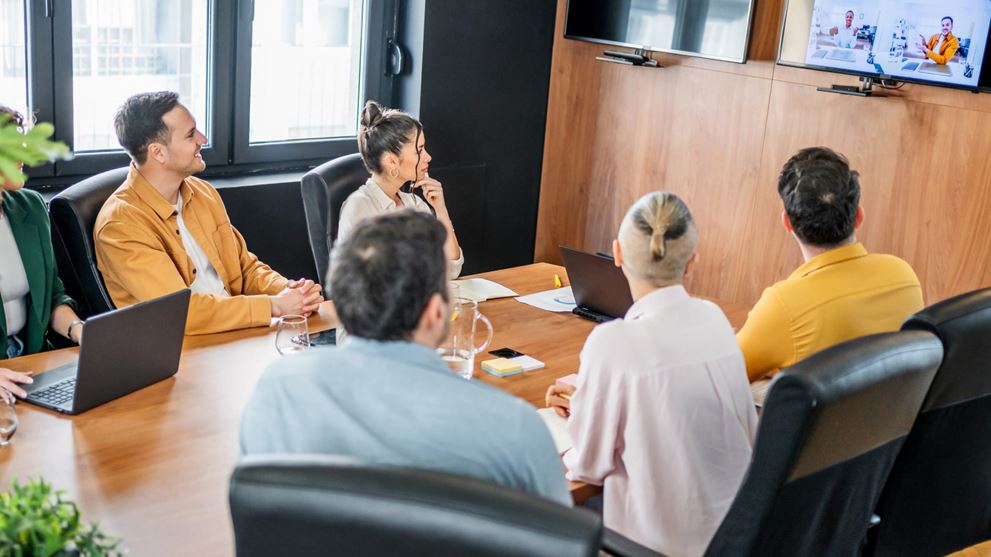 Insurance professionals participate in a hybrid meeting with remote colleagues.