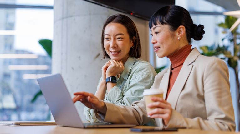 wo business professionals reviewing information on a laptop, representing fraud prevention, risk management, and digital security.