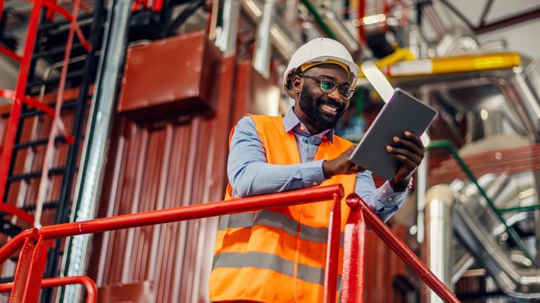Manufacturing professional using a tablet to monitor industrial operations and equipment in a production facility.