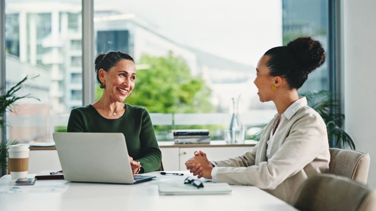 Two business professionals discussing regulatory compliance and risk management during a meeting in a modern office.