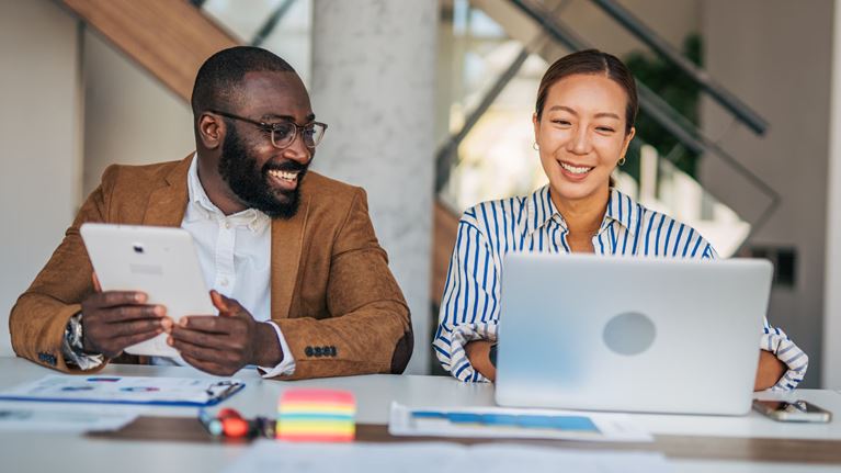 Financial professionals using a laptop and tablet to collaborate on AI-driven financial crime model tuning and automation.