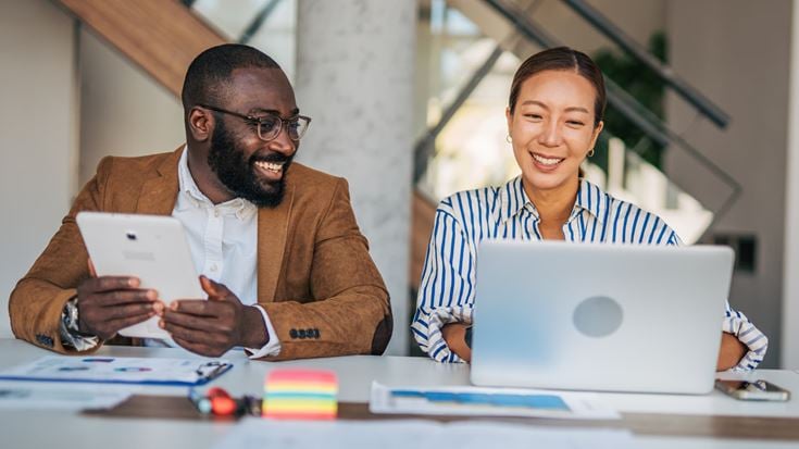 Financial professionals using a laptop and tablet to collaborate on AI-driven financial crime model tuning and automation.