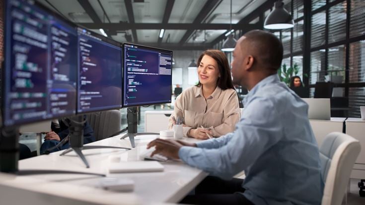 IT and information security professionals collaborate at computer workstations to strengthen cyber resilience and risk management.