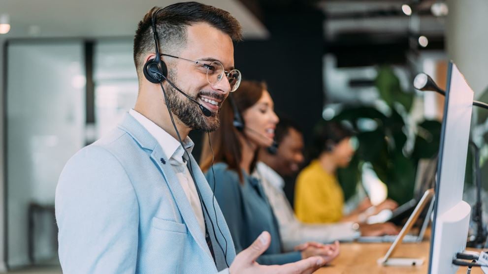 Customer service representative wearing a headset while working at a computer.